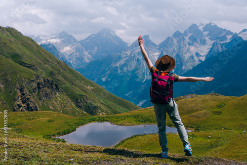 A woman Stand with arms spread out to the sides. at the Koruldi Lake with view on mountain Mestia in the Caucasus Mountain Range, Upper Svaneti, Country of Georgia. Wanderlust. Trekking. Copy space