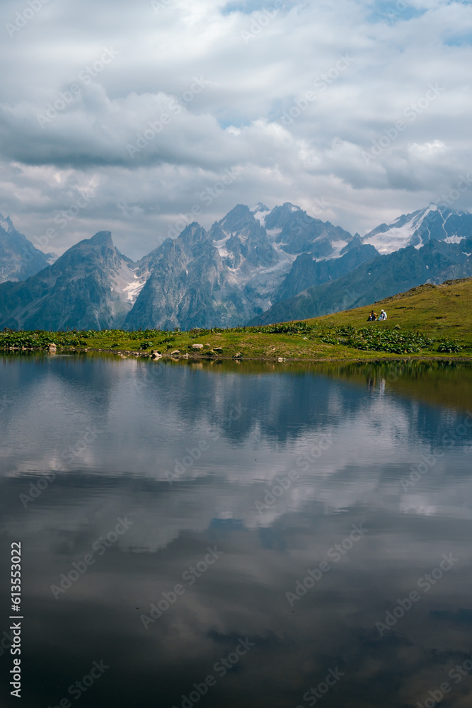 Koruldi lakes in Caucasus mountains, Mestia, Svaneti region, Georgia. Summer day, green hills, high mountain pasture for livestock, white, snow-capped mountain peaks. Nature and travel.