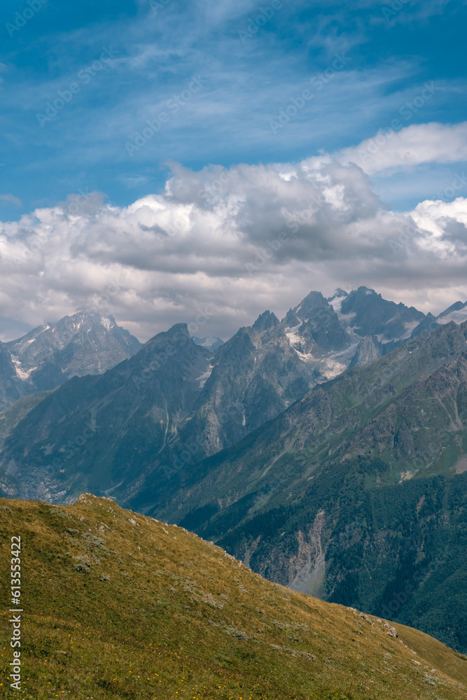View of mountain tops, warm summer day, clouds in the sky, way to Ushba mountain and Koruldi lakes. Concept of vacation and travel to Georgia. Nature, Mestia, Svaneti mountains. Vertical photo
