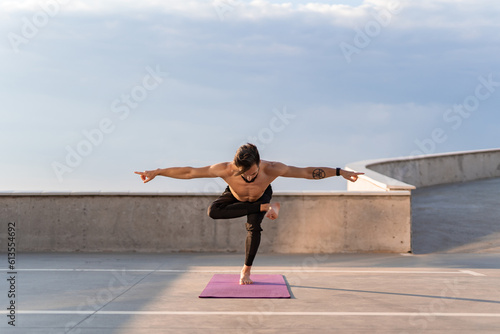attractive hansome man with athletic strong body doing morning yoga asana outdoors