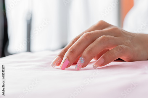 detailed view of a woman's hand with her nails decorated with a press-on manicure
