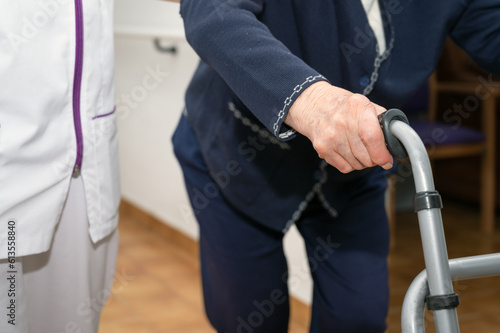 Nurse assists her senior patient on folding walker. Recuperation for elderly, seniors care, nursing home. High quality photo © herraez