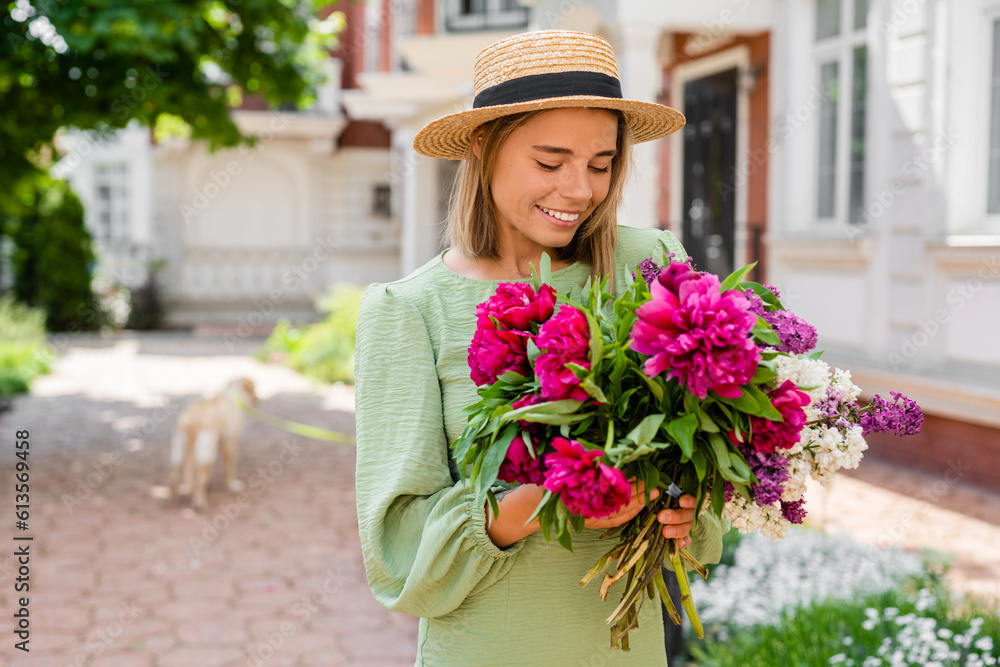 Fototapeta premium beautiful young woman in summer style outfit smiling happy walking with flowers in city street