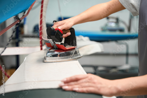 Foto Laundry service worker carefully ironing clothes to get rid of wrinkles