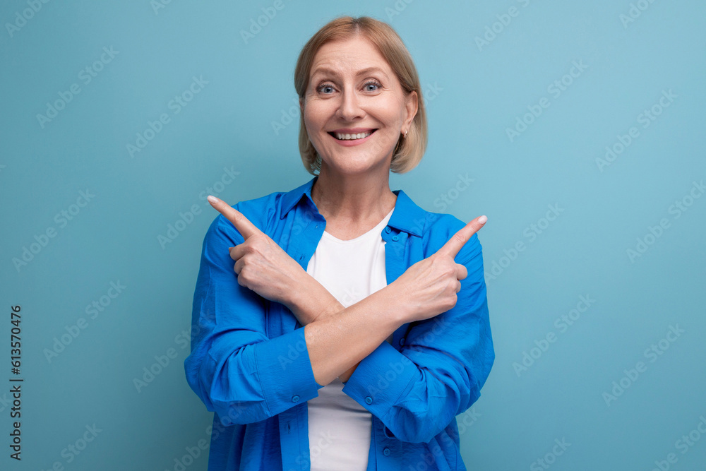 mature woman shows her hands in different directions on a blue background with copyspace mature woman shows her hands in different directions on a blue background with copyspace