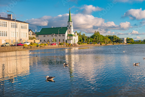 Historical and touristic downtown in Reykjavik at sunset in Iceland. Cityscape at golden hour and blue sky at inner lake around Tjornin city park in the downtown.