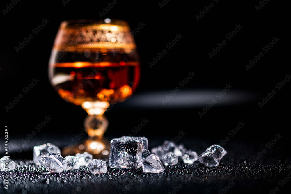 Glass with cognac and ice on a dark background. the concept of alcoholism and drinking Glass with cognac and ice on a dark background. the concept of alcoholism and drinking