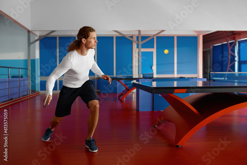 Fototapeta Naklejka Na Ścianę i Meble -  Young man table tennis player kicking ball with racket in motion