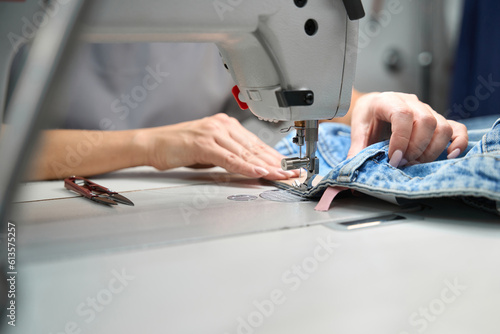 Seamstress sewing tags to clothes on sewing machine