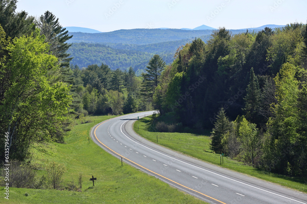 turn in a road with blue hills in the background on a clear day (trees, forest, country highway) no traffic, travel, getaway to new england