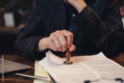 Lawyer or businessman stamping on legal deal contract in office, approval of certificate document public paper agreements at desk of notary or making a signs permit. Investment authority Law.