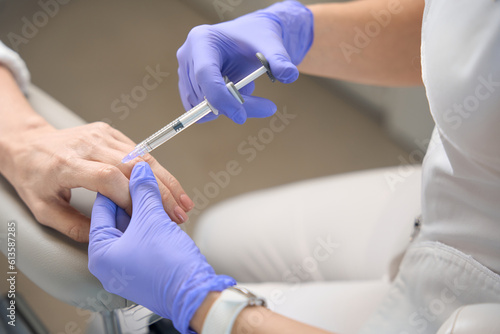 Closeup of beautycian hands in gloves making knuckle injection