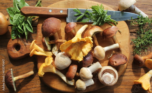 Photographie Mix of forest mushrooms on cutting board over old wooden table