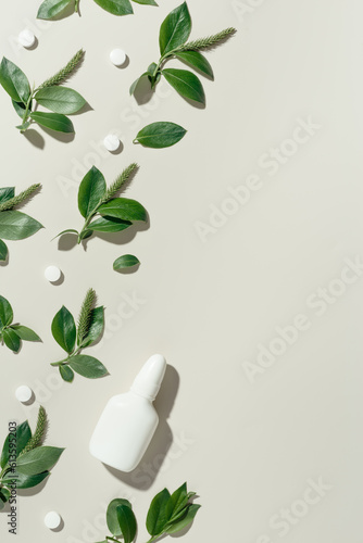 Seasonal spring allergies, new green branches tree with blooming catkins, nasal spray, antihistamine pills on beige Concept of treatment allergy to spring flowering. Aesthetic still life
