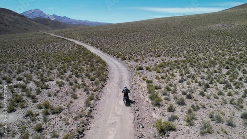 man riding motorcycle on dirt road alone photo