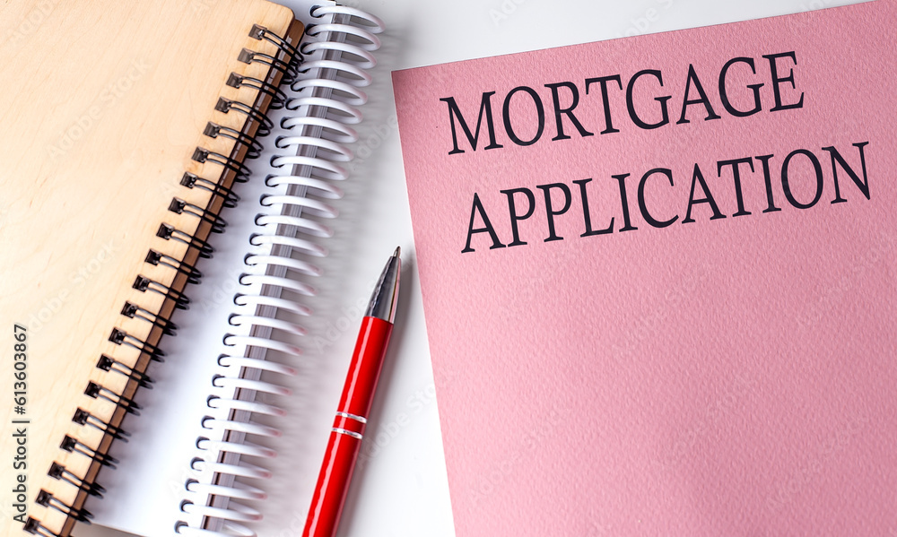 MORTGAGE APPLICATION word on the pink paper with office tools on white background MORTGAGE APPLICATION word on the pink paper with office tools on white background