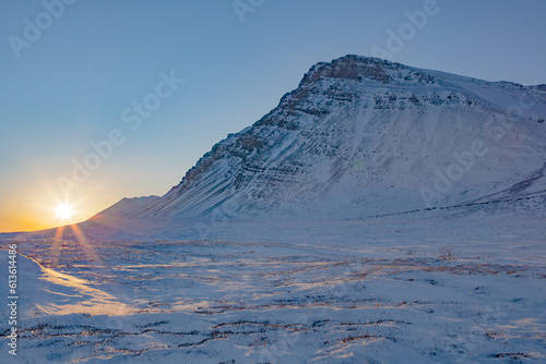 Frozen tundra and mountain range landscape in Alaska at sunset