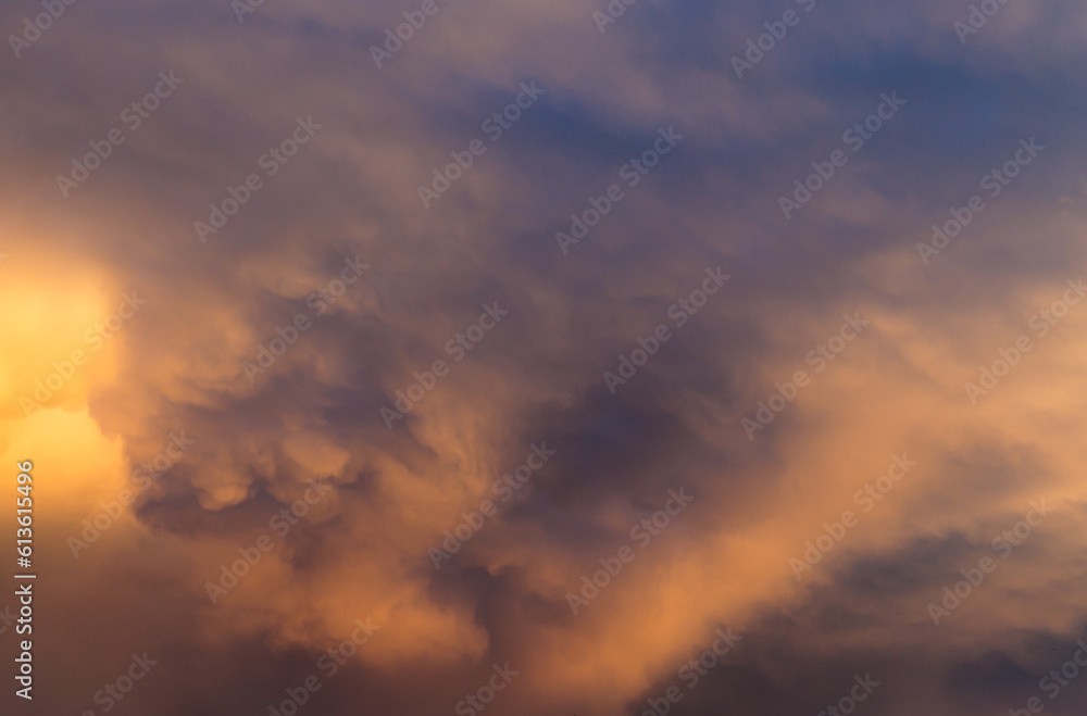 Blurred blue sky with orange sunset  clouds. Selective focus. Defocused skyscape with copy space.