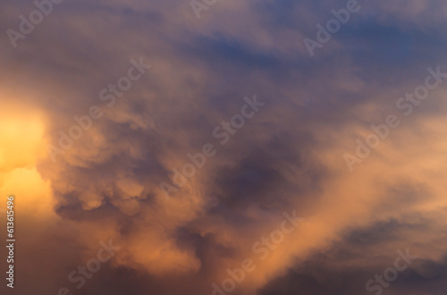 Blurred blue sky with orange sunset clouds. Selective focus. Defocused skyscape with copy space.