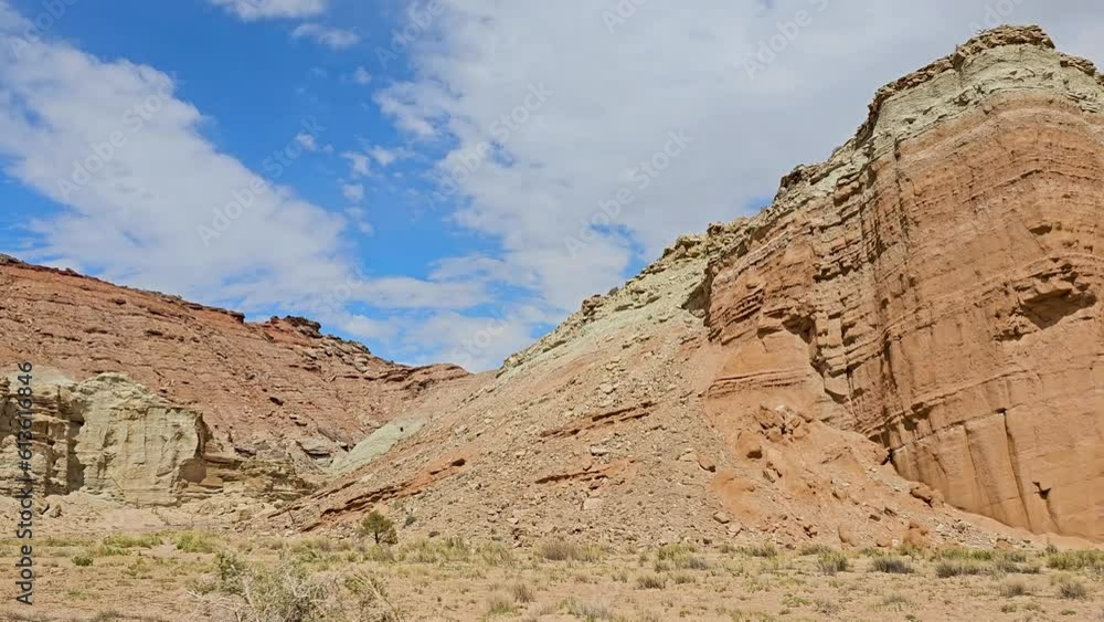 Drive Plate-Side view-Passing towering cliffs of multiple layers of sandstone under blue sky with clouds in the Miller Canyon area of the San Rafael Desert of the Colorado Plateau in Utah Drive Plate-Side view-Passing towering cliffs of multiple layers of sandstone under blue sky with clouds in the Miller Canyon area of the San Rafael Desert of the Colorado Plateau in Utah