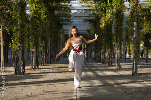 Latin and Hispanic girl, young and beautiful, dancing modern dance in the street outdoors. Dance concept, moonwalk, jumpstyle, shuffle, electrodance, hip hop, funky, popping.