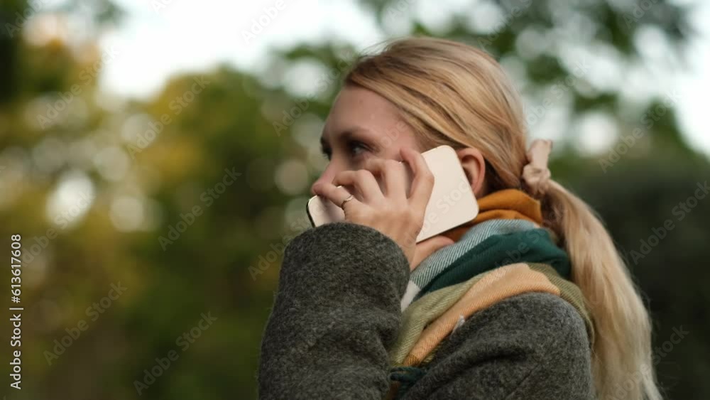 woman wearing scarf and coat talking on mobile phone outdoors. woman wearing scarf and coat talking on mobile phone outdoors.