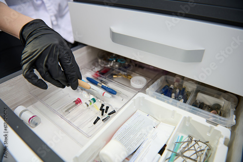 Принти на полотні Close-up hand of a dentist in black glove, taking out dental tool form the drawe