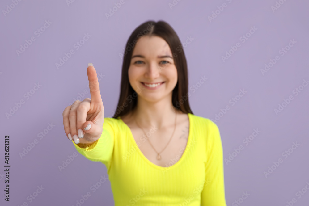 Young woman in bright shirt with raised index finger on lilac background, closeup Young woman in bright shirt with raised index finger on lilac background, closeup