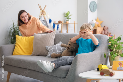 Little boy and nanny playing hide-and-seek at home
