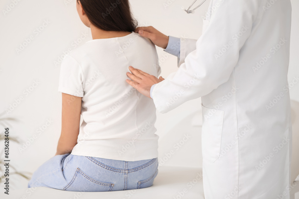 Naklejka premium Male doctor checking posture of young woman in clinic