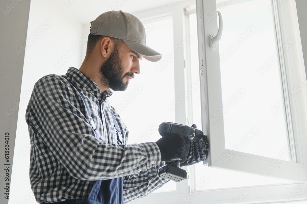 Worker installing plastic window indoors Worker installing plastic window indoors