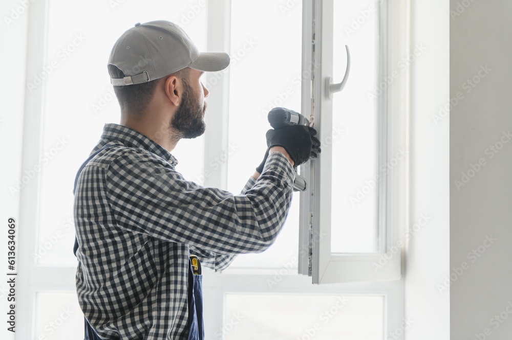 service man installing window with screwdriver service man installing window with screwdriver