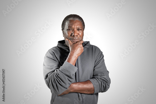 Portrait of senior black man with hand on chin and arms crossed.