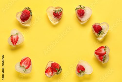 Frame made of fresh strawberry frozen in ice on yellow background