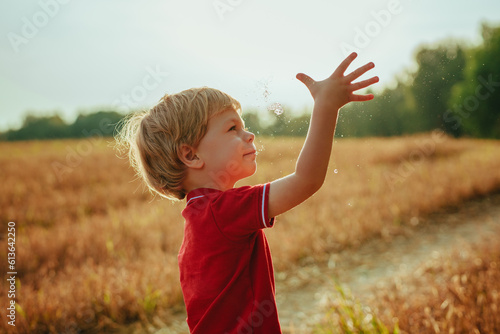 Little boy catches water droplets in the air