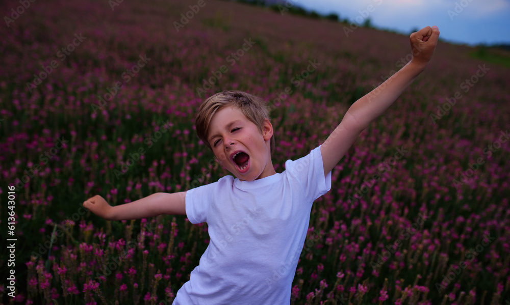 Happy boy stretching in flower meadow at twilight Happy boy stretching in flower meadow at twilight