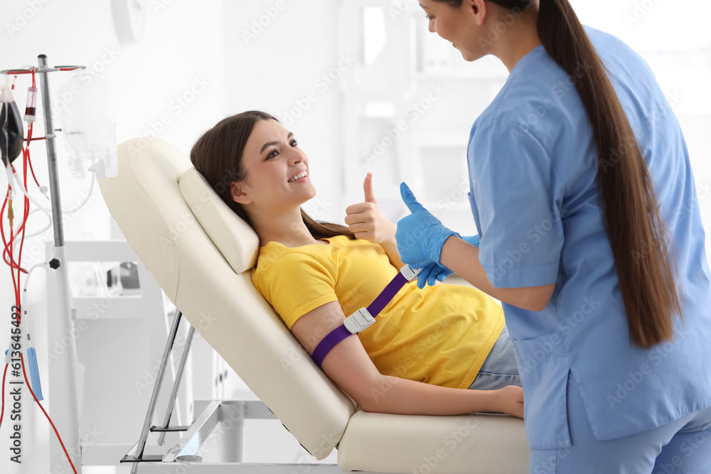 Obraz premium Female nurse preparing young donor for blood transfusion in clinic