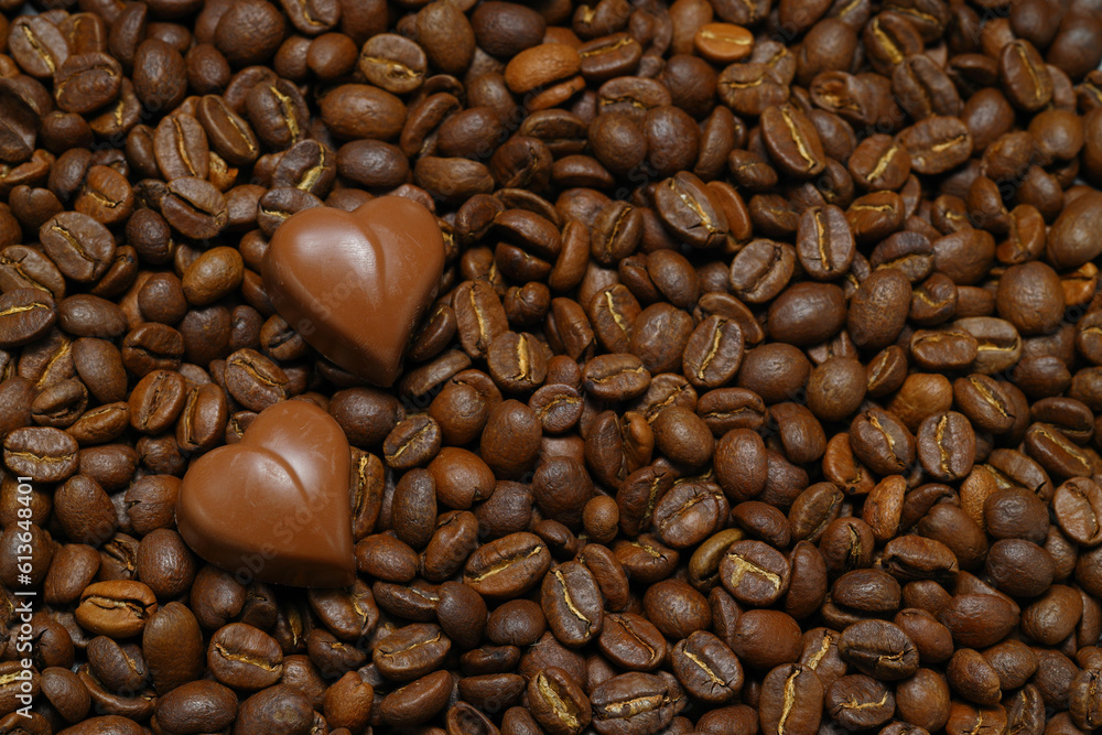Fototapeta premium Tiny chocolate in heart shape on coffee beans. Close up. 