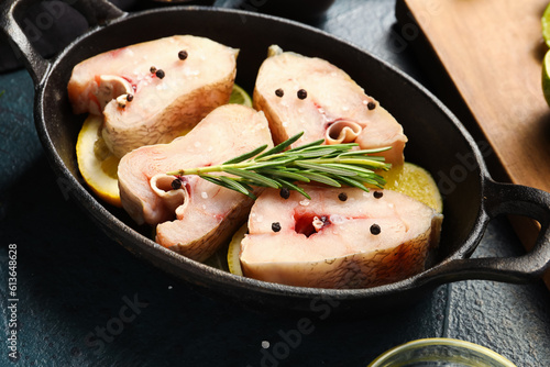 Baking dish with pieces of raw codfish on dark background photo