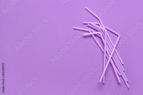 Lilac plastic straws on purple background