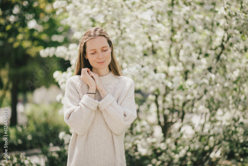 Young beautiful woman with freckles near blooming spring trees.