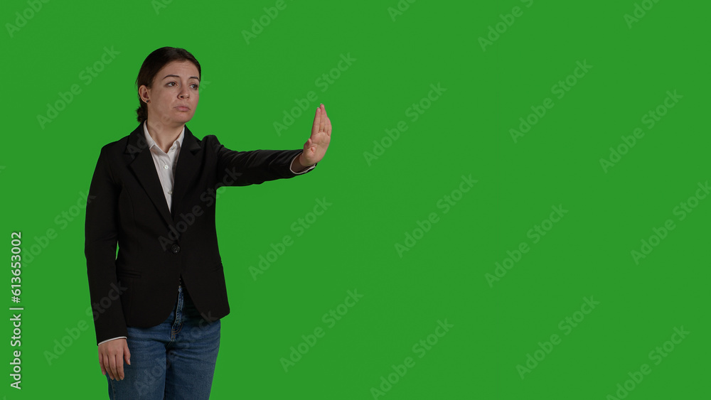Side view of businesswoman showing no sign with palm, expressing negative gesture and denial in studio. Female worker in office suit doing rejection and refusal symbol over greenscreen. Side view of businesswoman showing no sign with palm, expressing negative gesture and denial in studio. Female worker in office suit doing rejection and refusal symbol over greenscreen.