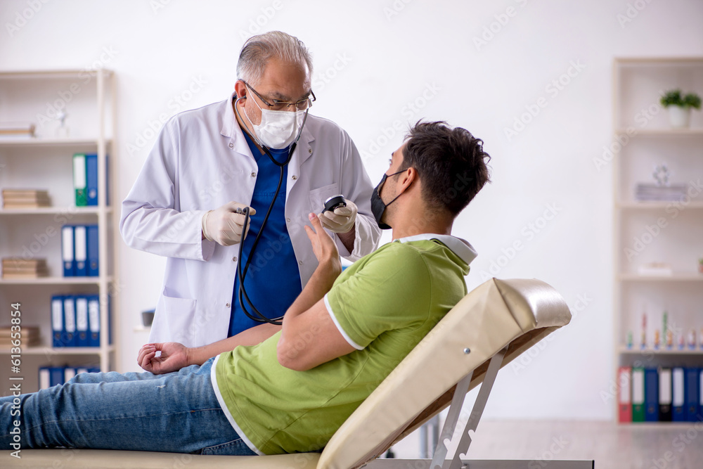 Old male doctor measuring young patient's blood pressure Old male doctor measuring young patient's blood pressure