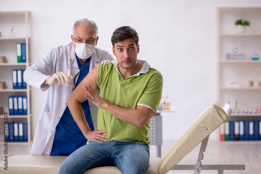 Obraz premium Young male patient visiting old male doctor in vaccination conce