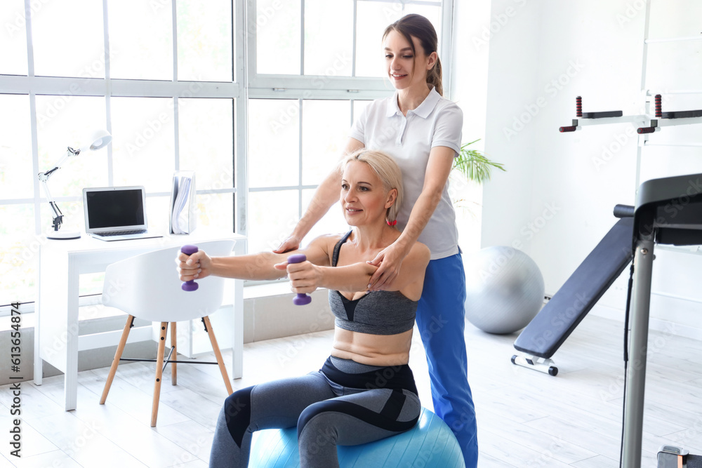 Mature woman training with dumbbells and female physiotherapist rehabilitation center Mature woman training with dumbbells and female physiotherapist rehabilitation center