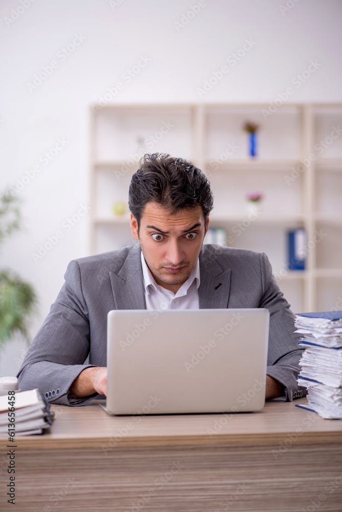 Young male employee and too much work in the office Young male employee and too much work in the office