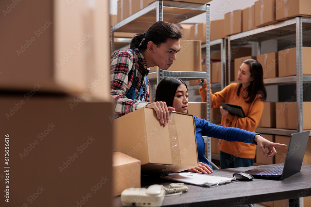Storehouse package handler and shipment manager checking order pick ticket on laptop. Warehouse asian employees talking about logistics schedule and looking at plan on computer Storehouse package handler and shipment manager checking order pick ticket on laptop. Warehouse asian employees talking about logistics schedule and looking at plan on computer