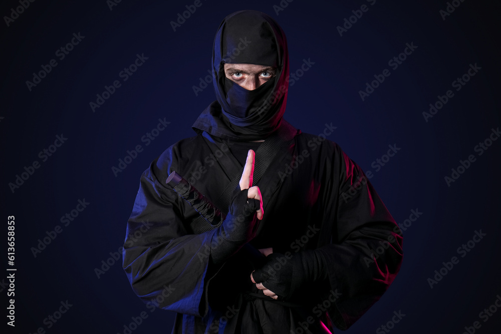 Male ninja with sword on black background