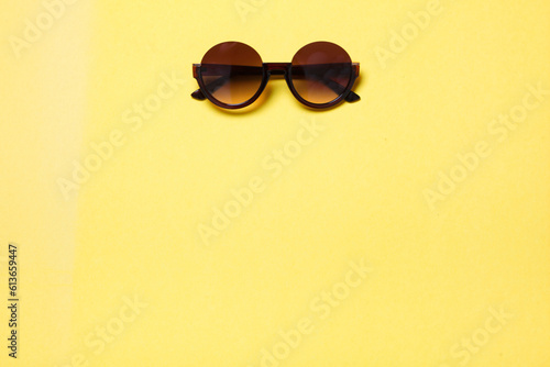 luxury fashionable sunglasses lying on yellow background, flatlay top view