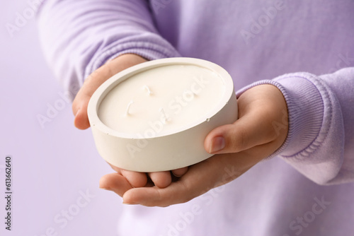 Woman holding candle on purple background, closeup